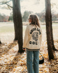 Person wearing a 'Good Lion Golf' jacket in a forest setting