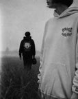 Two people wearing hoodies with visible branding in a foggy field.