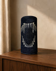 A black cylindrical denim driver cover with a white hand-drawn lion fang design, standing on a wooden cabinet against a textured beige wall.