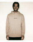 Man wearing a beige hoodie with text on a plain background