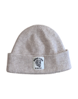 Beige knit beanie with a logo tag on a white background