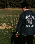 Person wearing a 'Good Lion Golf' jacket standing in a grassy field with trees in the background.