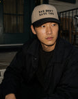 Person wearing a cap with text sitting outdoors