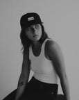 Person wearing a cap and tank top against a plain background