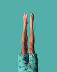Person wearing teal pants with animal patterns against a solid teal background
