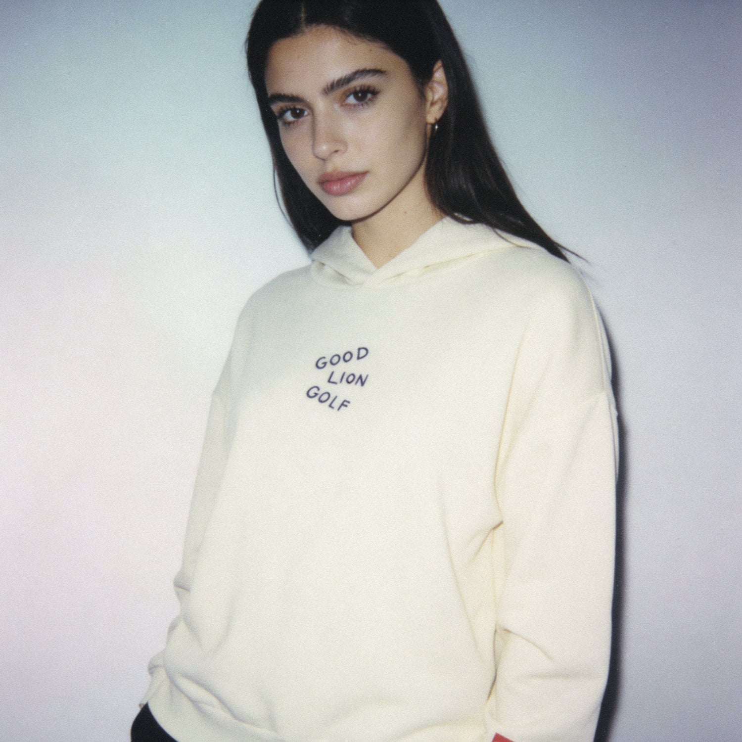 Person wearing a cream hoodie with text on a plain background