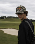Person wearing a camouflage cap and black shirt on a golf course