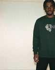 Person wearing a green sweatshirt with a logo against a plain background