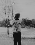Person playing golf on a course with trees and open sky in the background