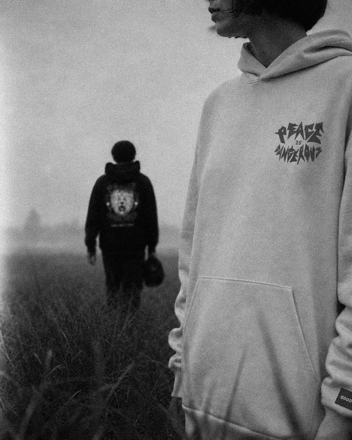Two people wearing hoodies with visible branding in a foggy field.