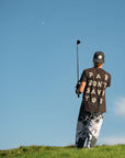 Person on a golf course holding a club with a clear blue sky in the background