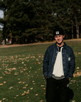 Person standing on a grassy field with trees in the background