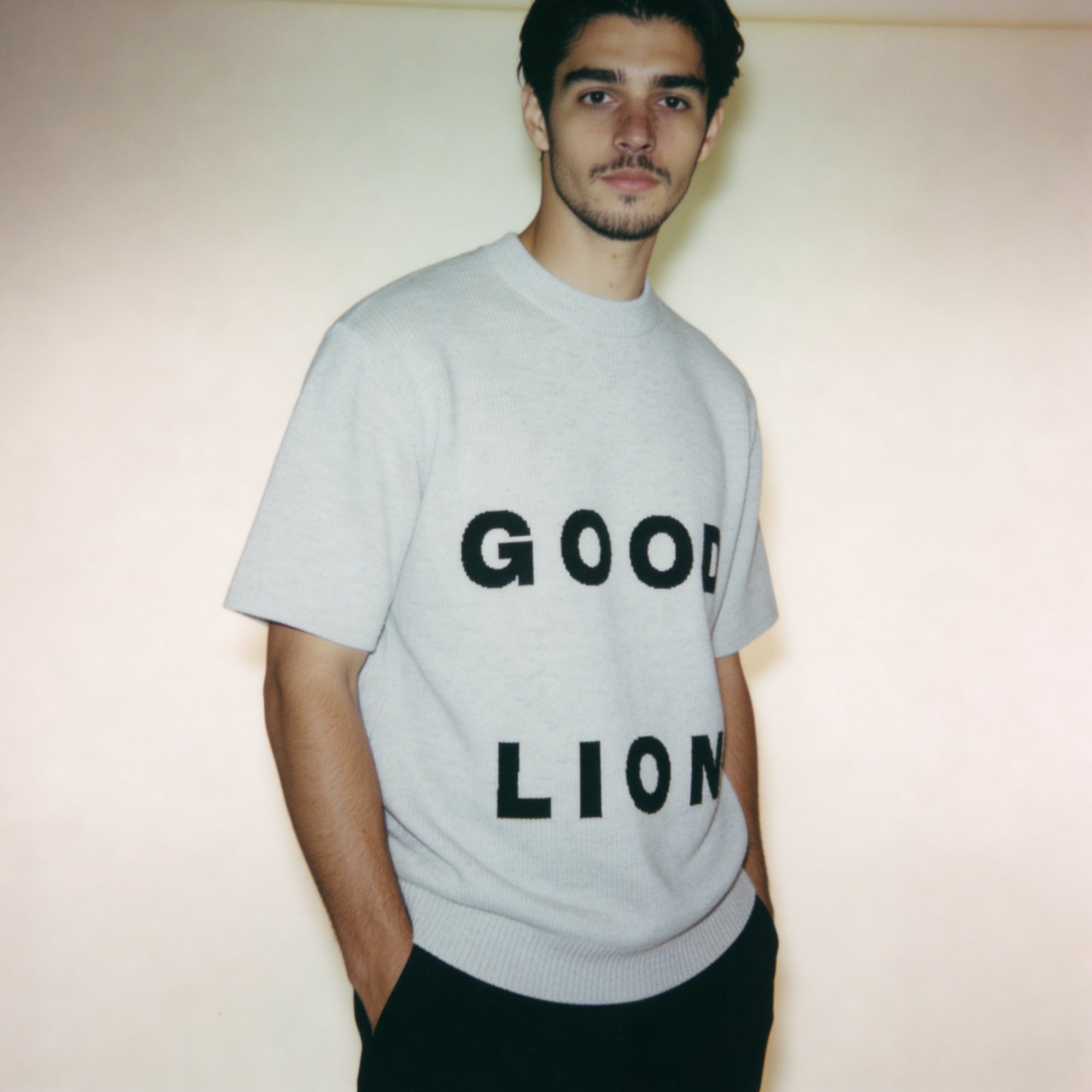 Person wearing a gray t-shirt with 'GOOD LION' text against a plain background