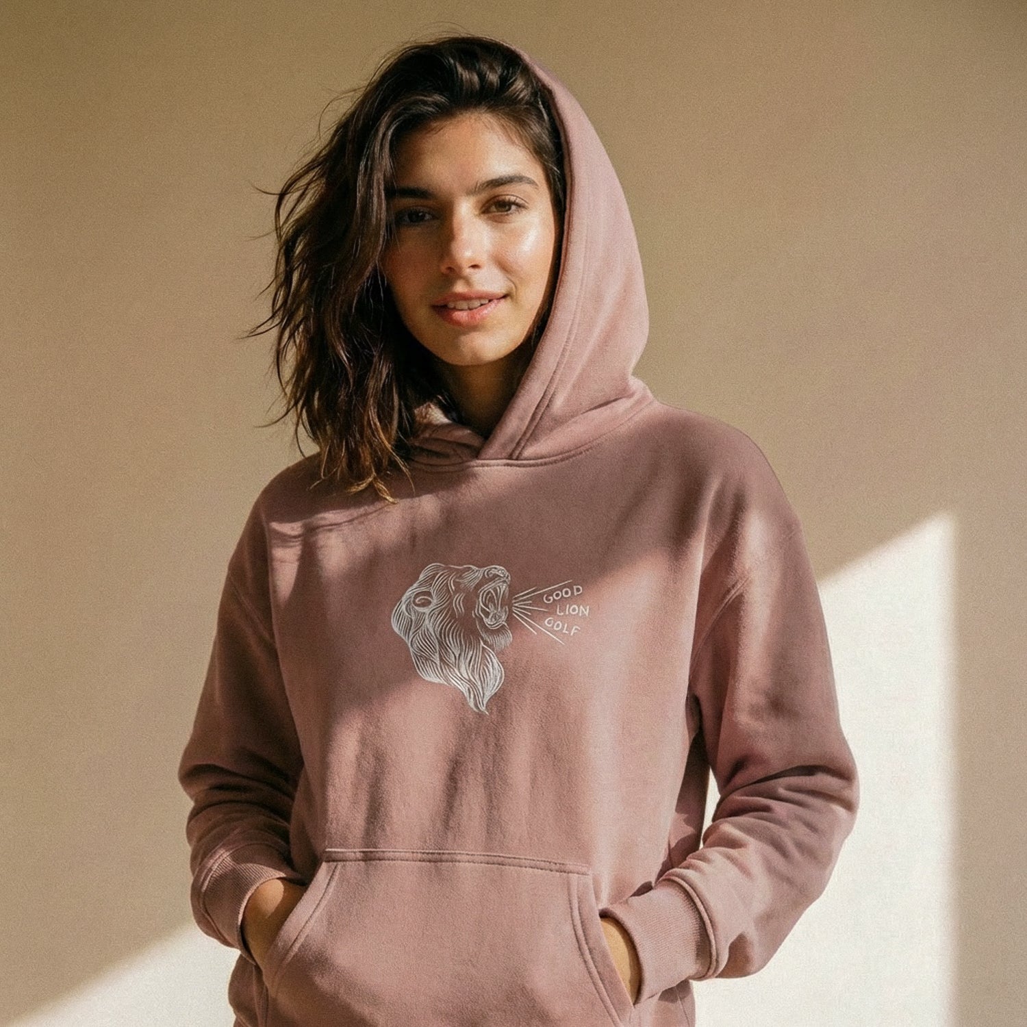 Woman wearing a pink hoodie with a graphic design on a beige background