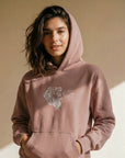 Woman wearing a pink hoodie with a graphic design on a beige background