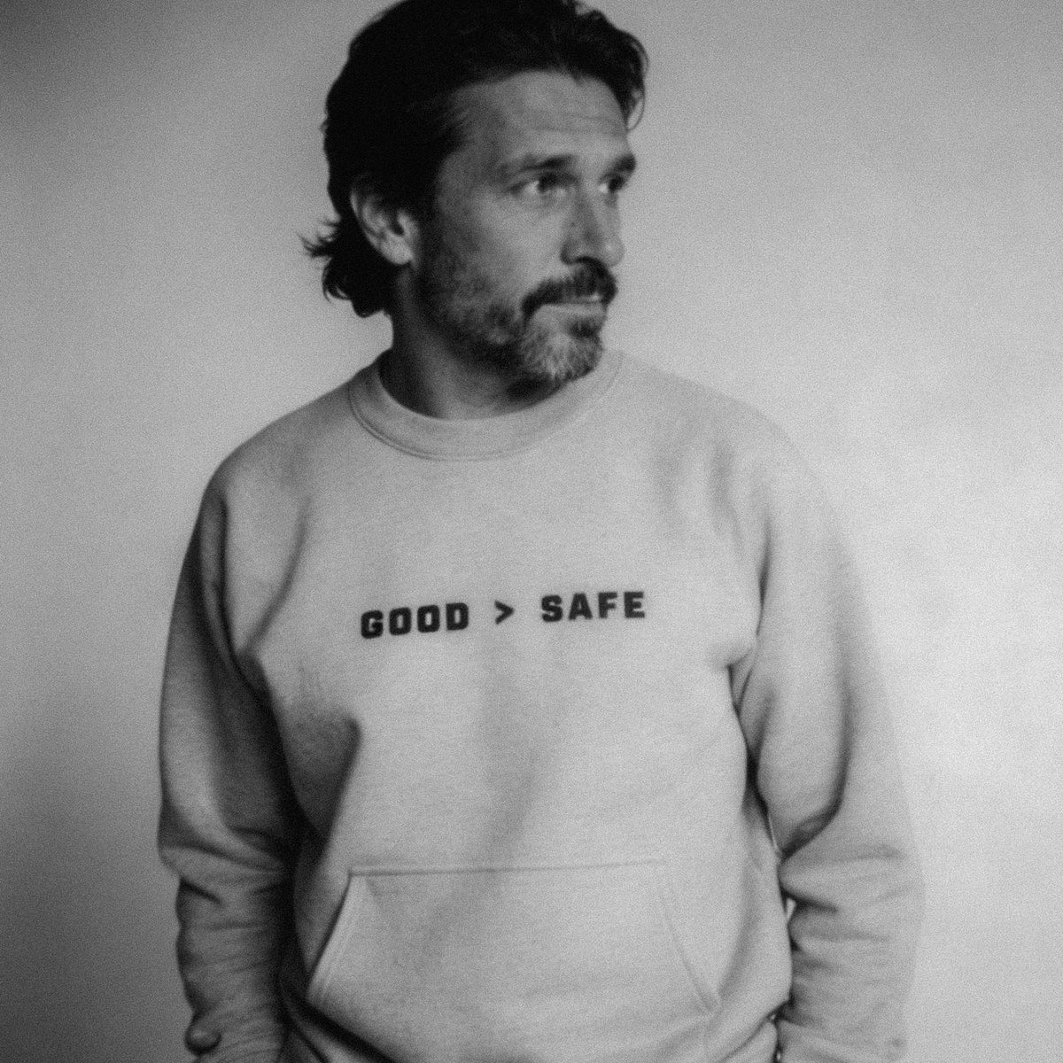Man wearing a sweatshirt with 'GOOD > SAFE' text on a plain background