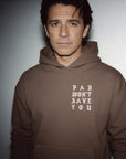 Man wearing a brown hoodie with text on a plain background