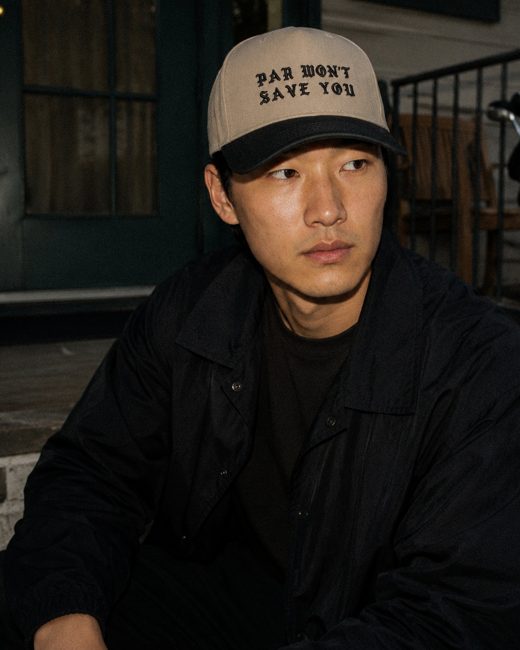 Person wearing a cap with text sitting outdoors