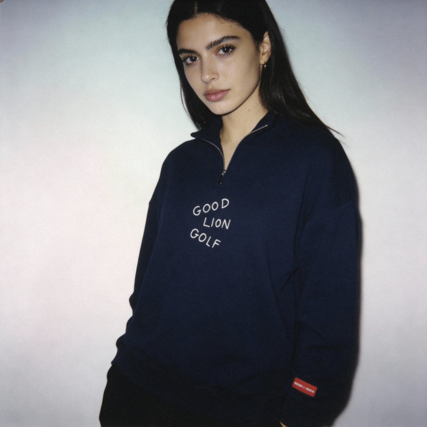 Person wearing a navy blue sweatshirt with 'Good Lion Golf' text on a plain background