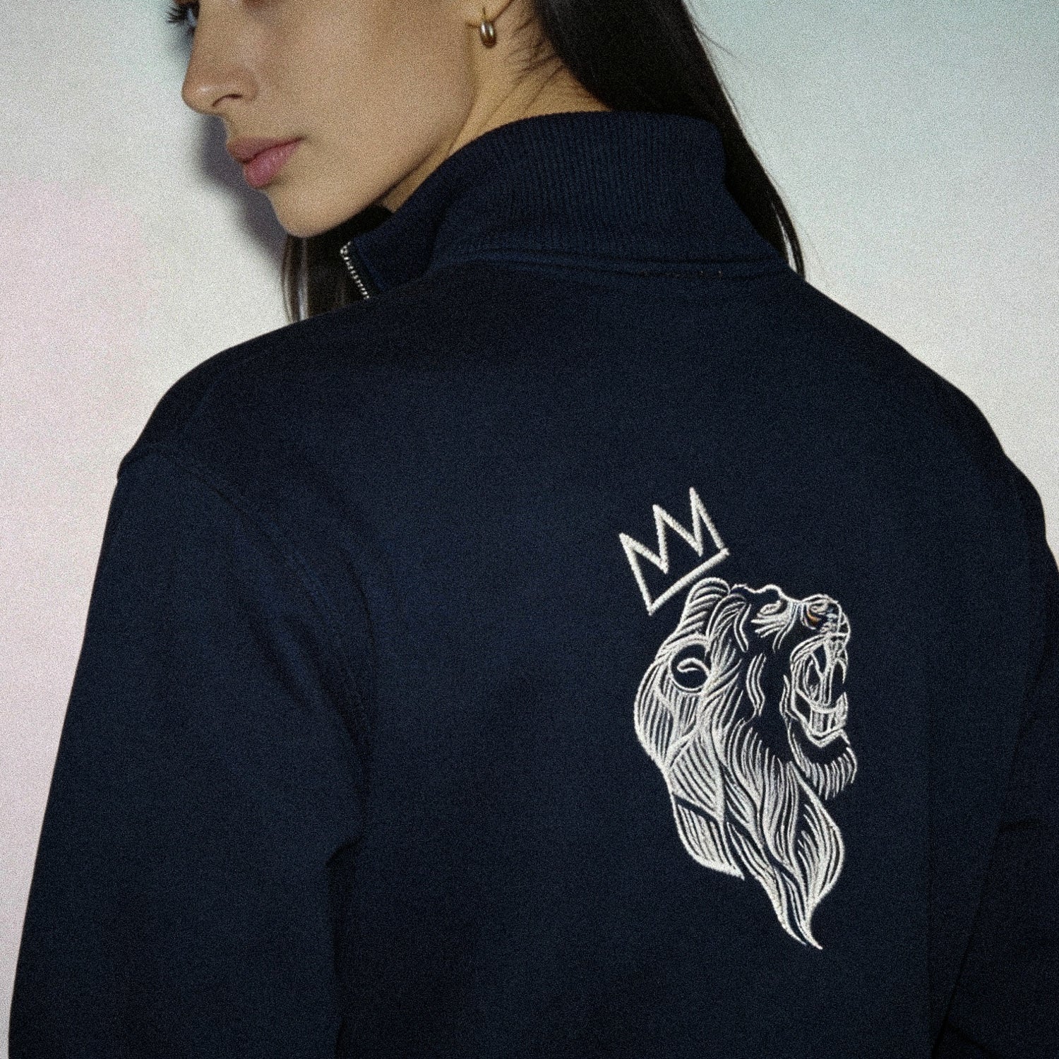Navy blue jacket with a white lion emblem and crown on the back, worn by a person.