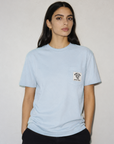 Woman wearing a light blue t-shirt with a small logo on a plain background