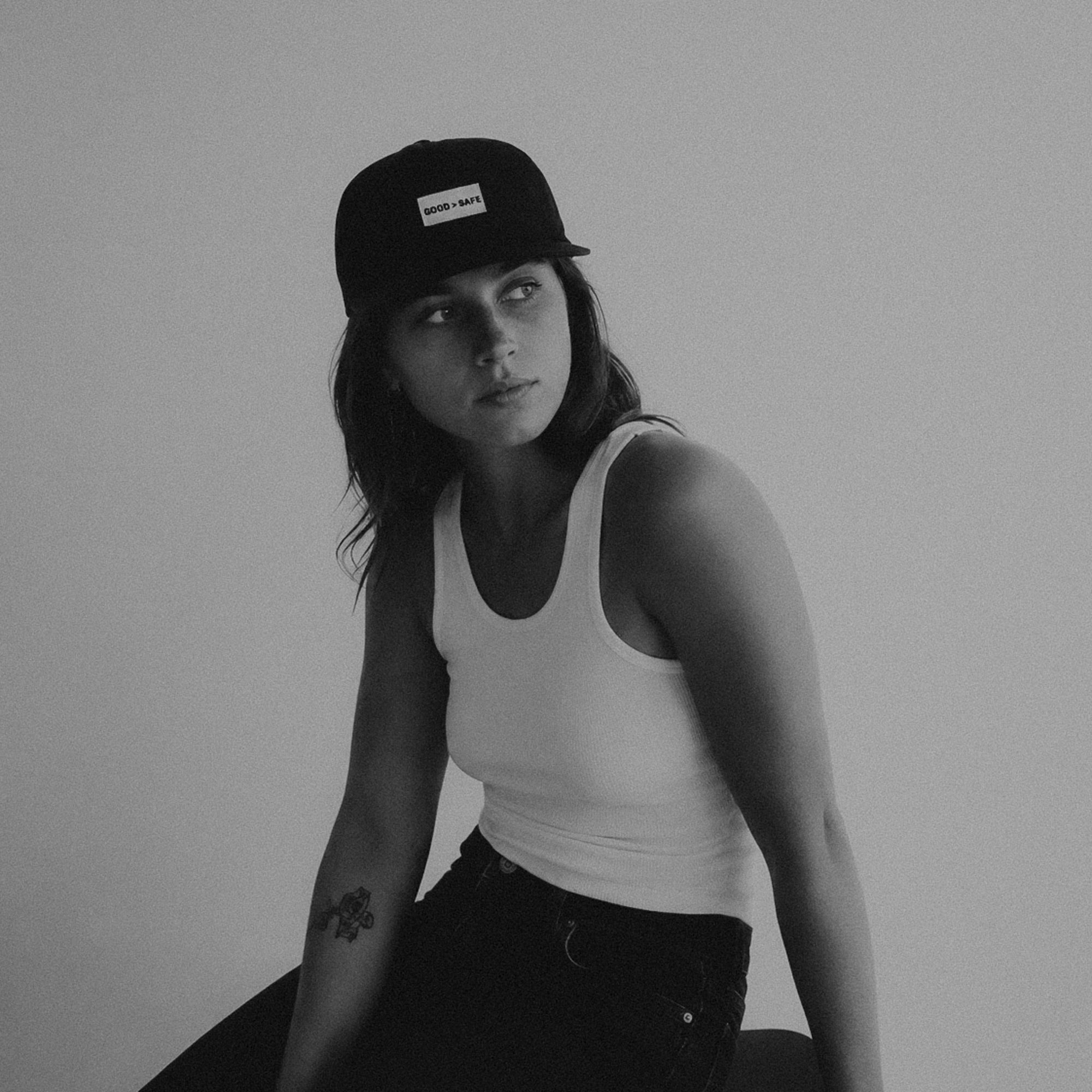 Person wearing a cap and tank top against a plain background