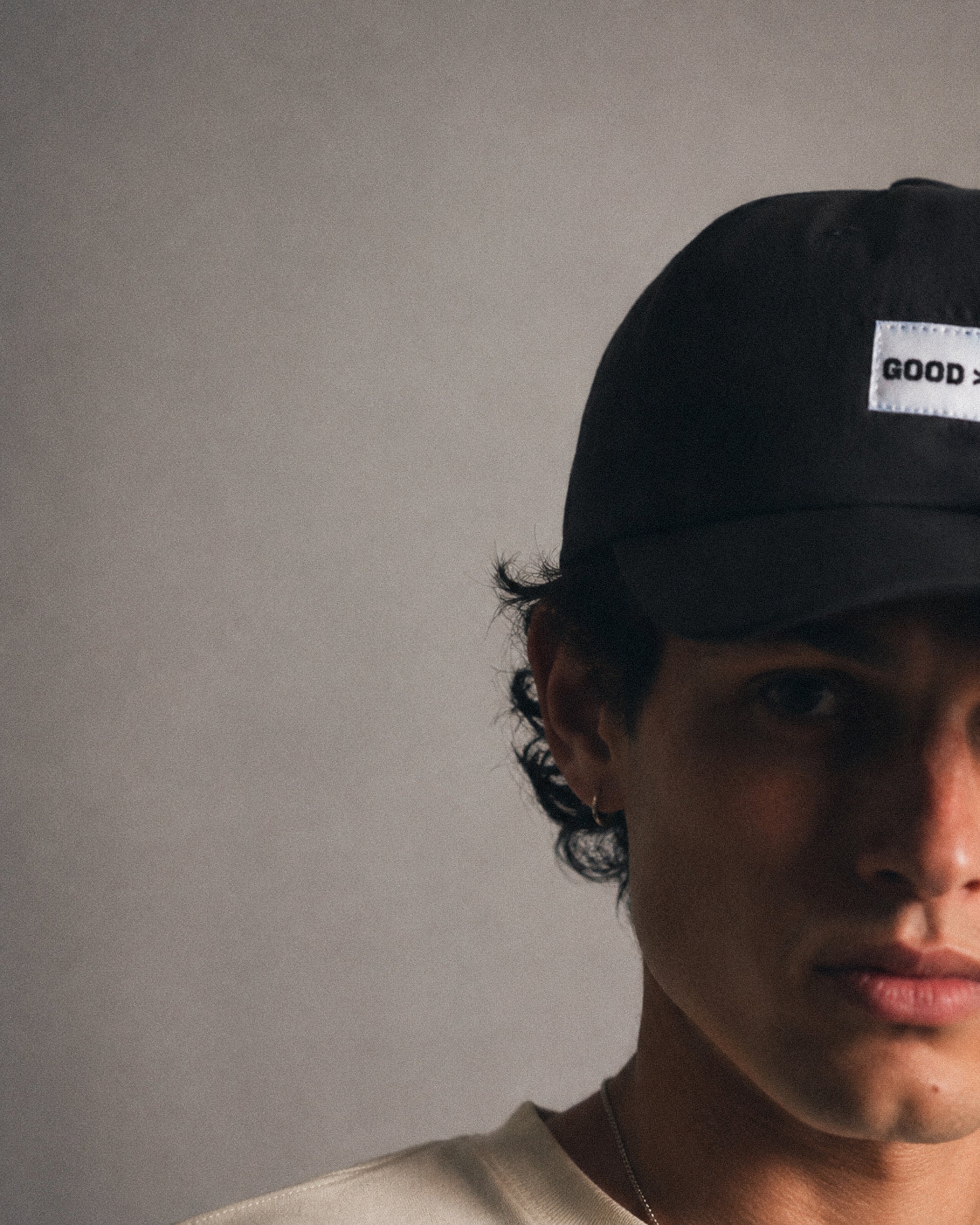 Person wearing a black cap with a visible brand logo against a plain background