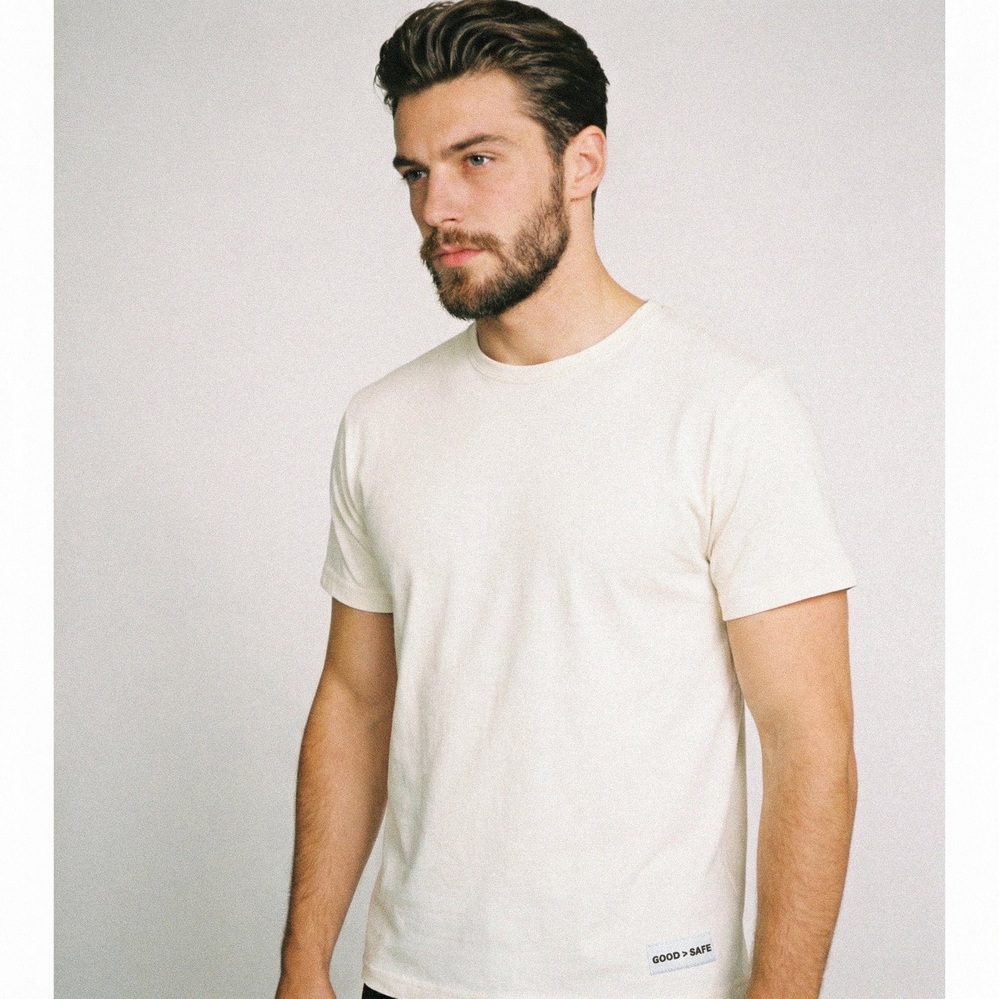 Man wearing a plain white t-shirt against a light gray background