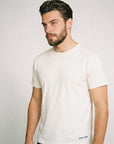 Man wearing a plain white t-shirt against a light gray background